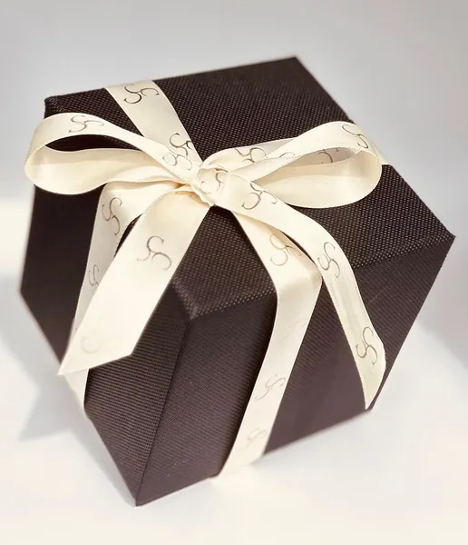 A dark brown square presentation box with cream ribbon